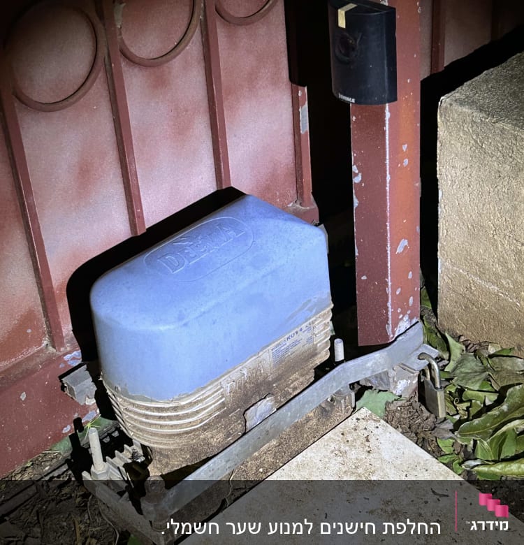 מנוע שער חשמלי עם כיסוי כחול ליד עמוד מתכת